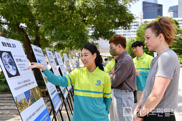 여의도한강공원에서 펼쳐진 거리캠페인에 참여한 외국인이 패널 내용을 경청하고 있다.