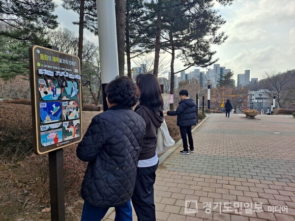 충훈공원 내 백세건강길 산책로 안내판을 살펴보는 안양시민들.